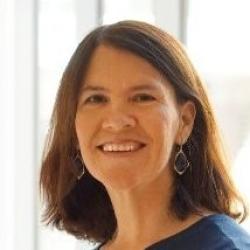 This image is a headshot showing Karen Peterson, who has brownish red hair that is shoulder length and she is smiling.